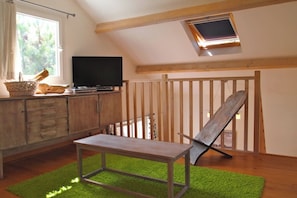 A room with a television on a wooden cabinet, a bench, and a green rug.