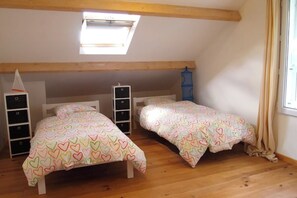 A bedroom with two beds, a skylight, and a window with curtains.