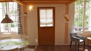 Una habitación con una puerta de madera, una mesa redonda con sillas y un sillón estampado.