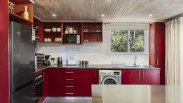 Una cucina moderna con mobili rossi, elettrodomestici in acciaio inossidabile e una finestra che lascia entrare luce naturale.