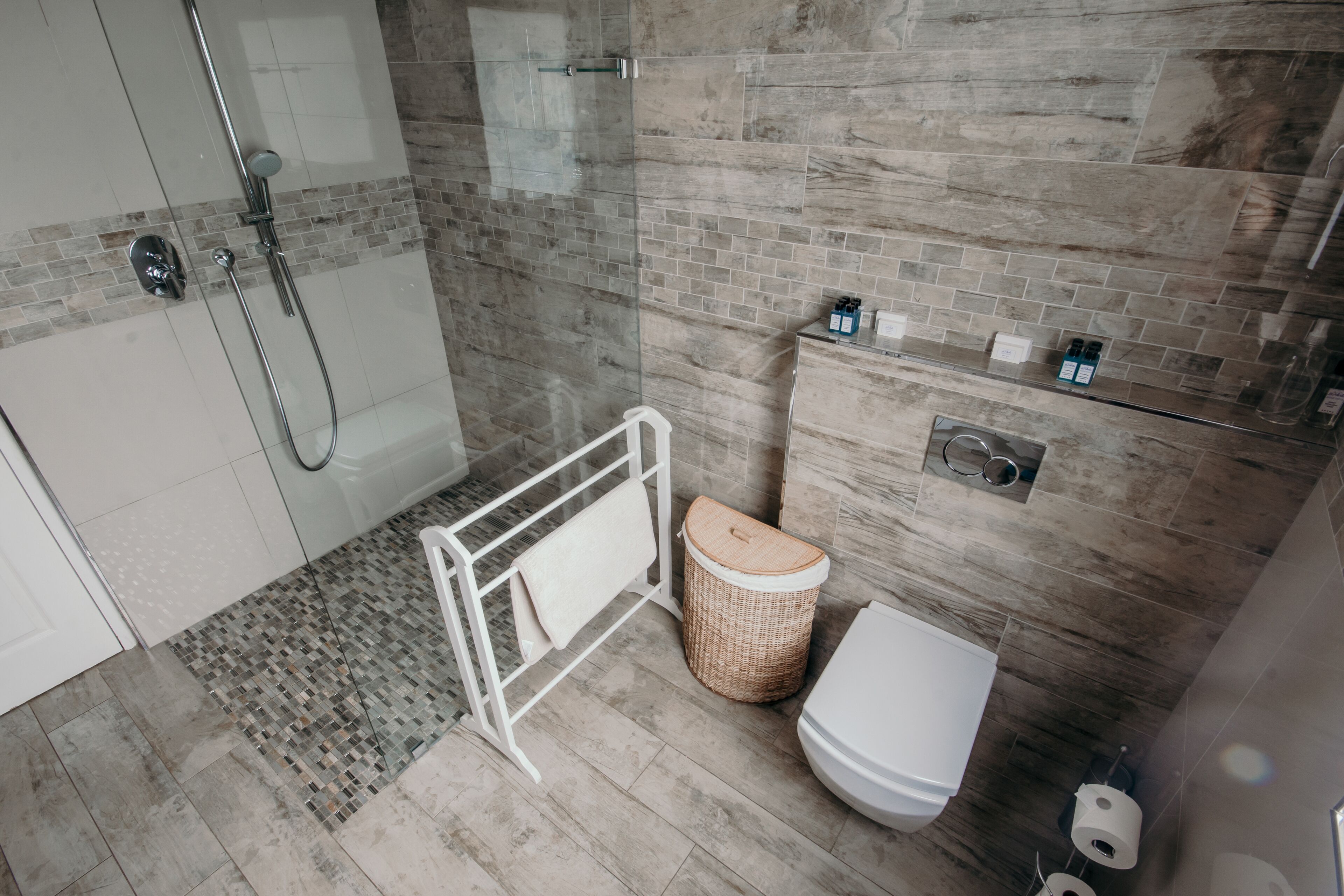 A modern bathroom with a shower, toilet, and storage cabinet.