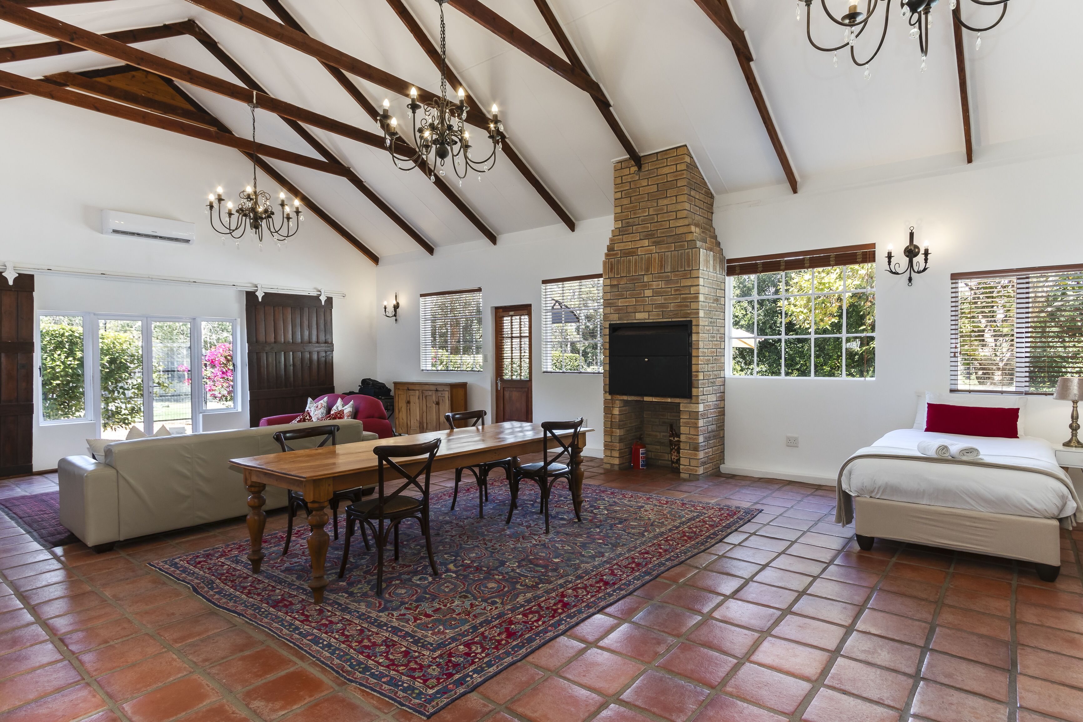 Amplia sala de estar con chimenea, comedor y dormitorio con una cama grande.