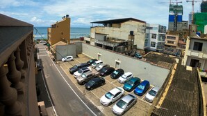 A parking lot with multiple cars, a view of the ocean, and buildings with construction cranes in the background. - Private Cozy Spacious Studio in Colombo (Colombo)