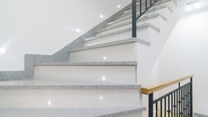 A staircase with granite steps and black railings, leading to an upper floor.