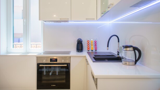 A modern kitchen with white cabinets, a Bosch oven, a sink, and a coffee maker.