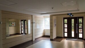 A hallway with a tiled floor, a glass door, and a black door with a sign indicating an exit.