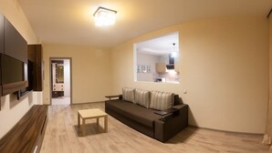 A modern living room with a sofa, a small table, and a TV mounted on the wall.