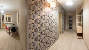 A hallway with patterned wallpaper, a dining area with a table and chairs, and a built-in shelving unit.