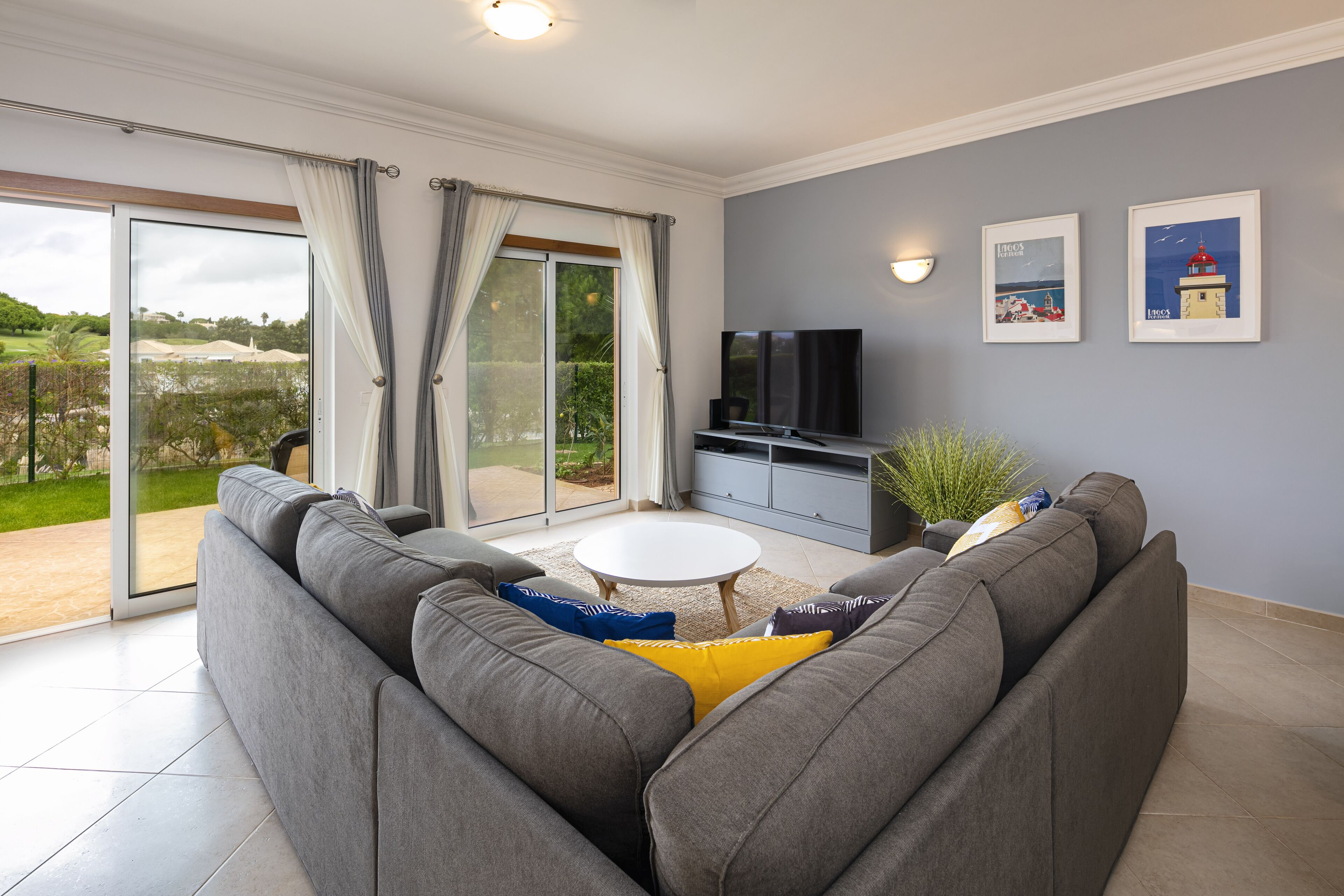 A modern living room with a grey sofa, a white coffee table, and a flat-screen TV.