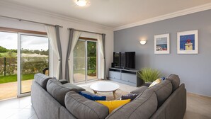 Ein modernes Wohnzimmer mit einem grauen Sofa, einem weißen Couchtisch und einem Flachbildfernseher.