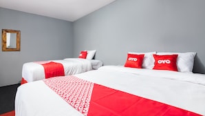 A hotel room with two beds, each with white and red bedding, and a mirror on the wall. - OYO 1765 Herman Homestay (Wonokitri)