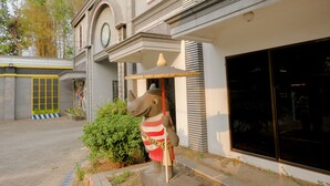Une façade d’immeuble avec une grande fenêtre, une statue de rhinocéros et une porte jaune ornée d’un motif quadrillé.