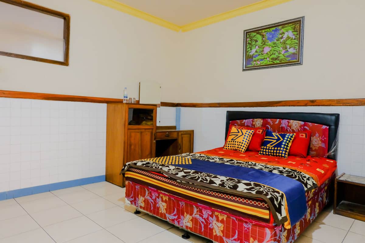 Un dormitorio con una cama, un armario de madera, una mesita y un cuadro colgado en la pared.