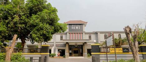 A hotel named "Hotel Dewi" with a traditional architectural style, featuring a prominent entrance and a signboard.