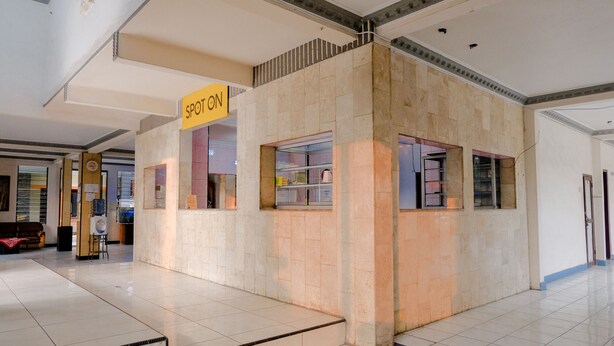 Un hall d’entrée spacieux, doté d’un sol carrelé, d’un comptoir de réception et d’une enseigne portant l’inscription « SPOTON ».
