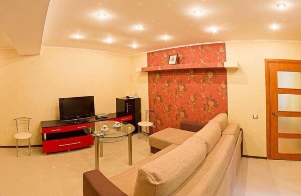 A living room with a sofa, a TV on a stand, a small table, and a red cabinet.