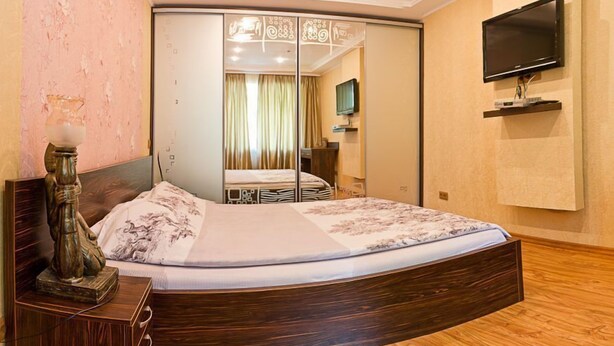 Un dormitorio con una cama grande, un televisor montado en la pared y un armario espejo.
