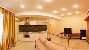Una sala moderna con sofá, una mesa de comedor y una cocina con armarios y televisor.