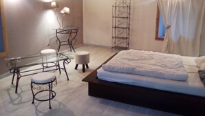 A bedroom with a bed, a desk, two chairs, a small table, and a ladder. - Chambres d'Hotes la Source (Mareuil-Sur-Lay-Dissais)