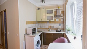 A compact kitchen with a washing machine, microwave, and a small sink. - Apart Kiev Starokievskiy pereulok 5-1 (Kyiv)