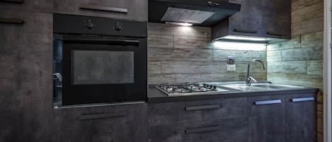 Design appartement | Privékeuken | Een koelkast, een oven, een kookplaat, kookgerei, borden en bestek