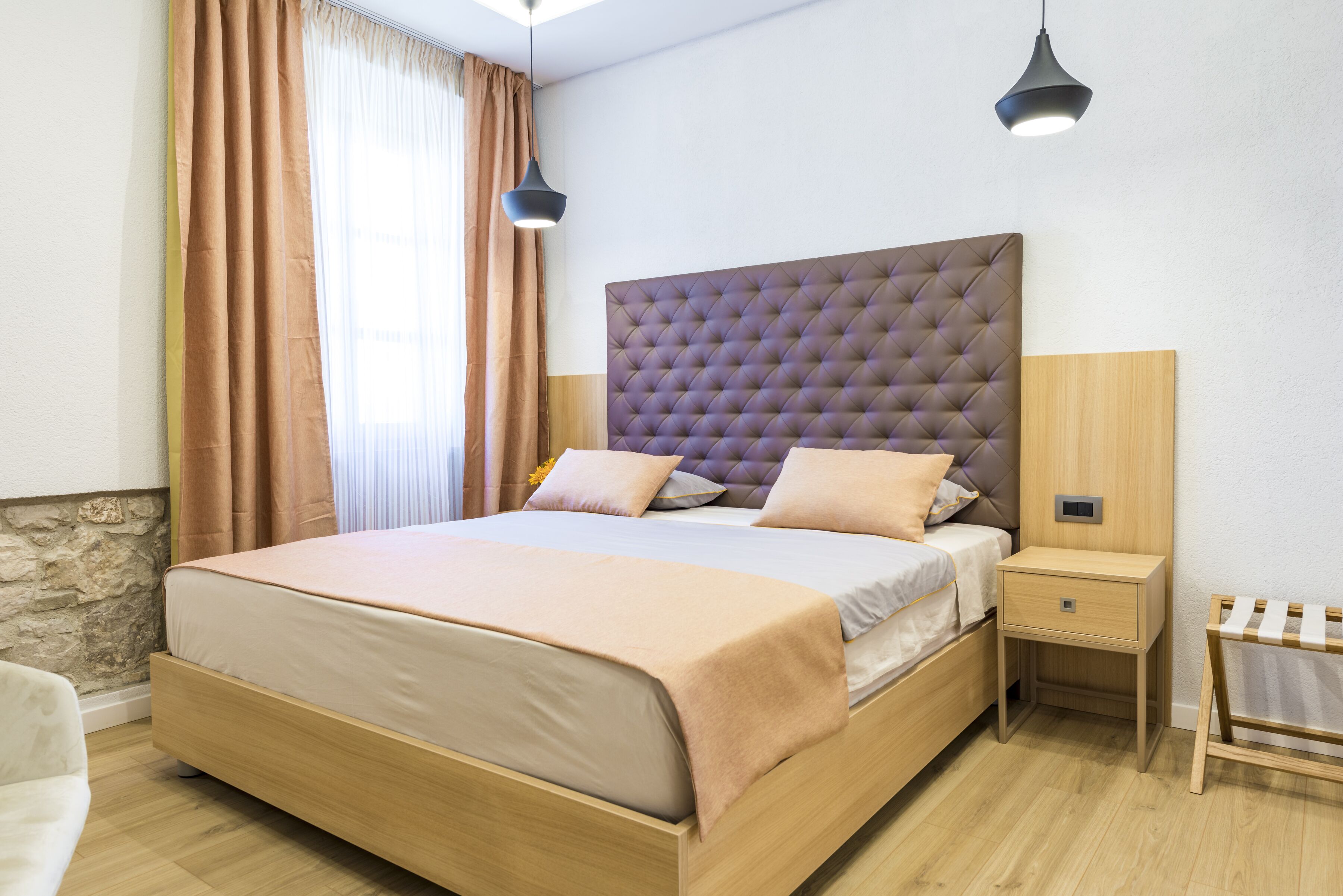 Un dormitorio ordenado con una cama grande, mesitas de noche e iluminación colgante.