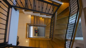 A modern staircase with wooden steps and metal railings, leading to a landing with a view of the interior.