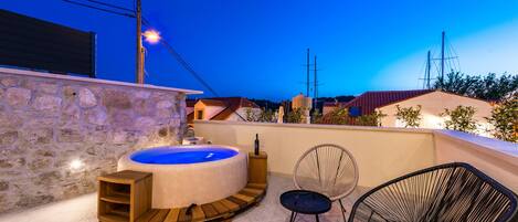 A stone wall, a hot tub, and two chairs in a patio area.