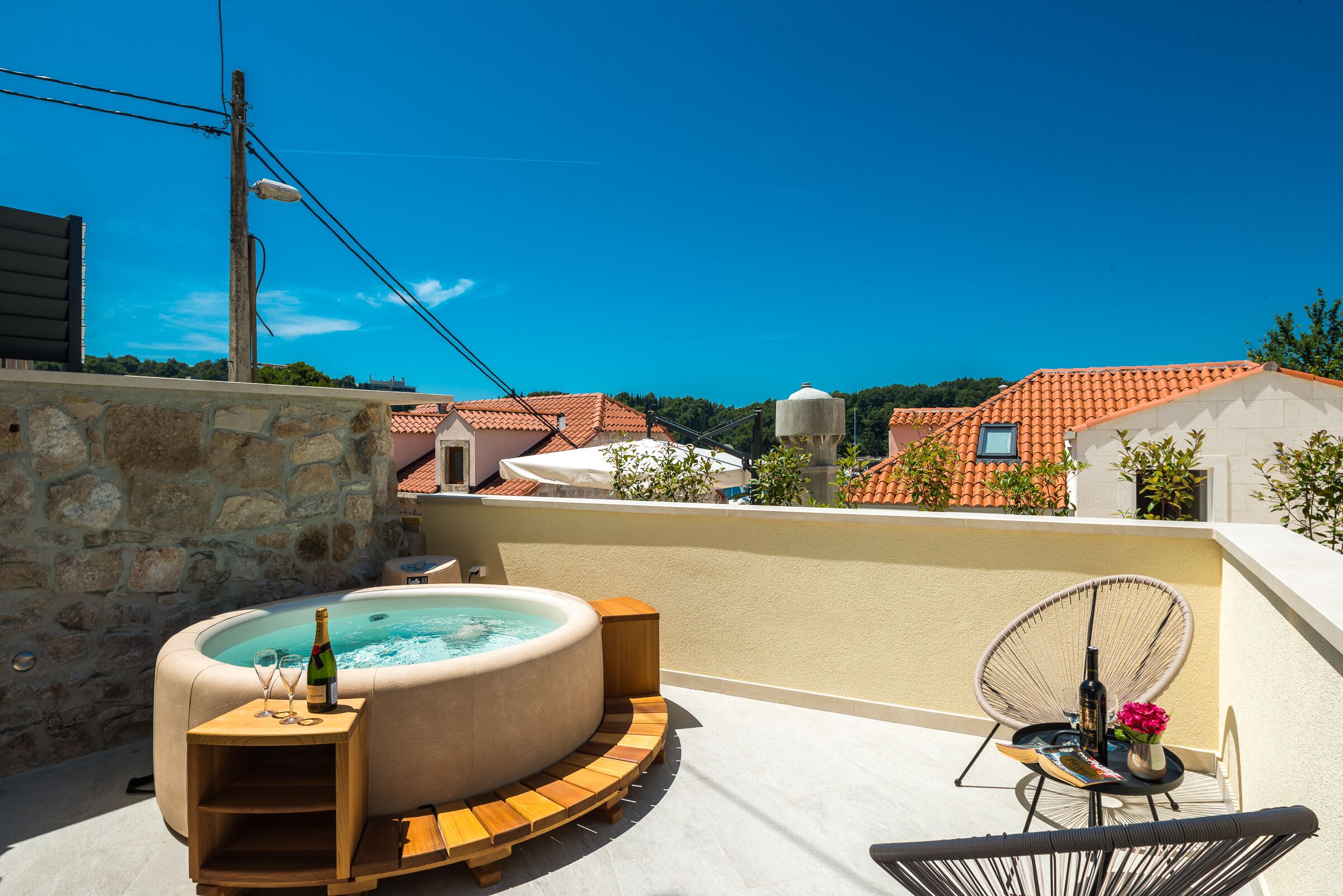 Una terraza en la azotea con hidromasaje, asientos de madera y una silla.