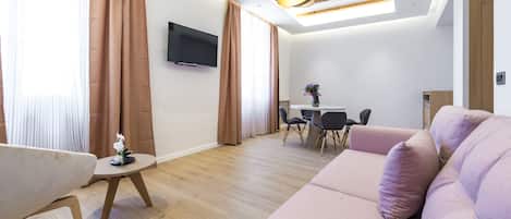 Una sala moderna con un sofá, una mesita y un televisor montado en la pared.