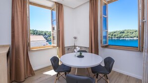 Una habitación con una mesa redonda, cuatro sillas y ventanas grandes con cortinas.