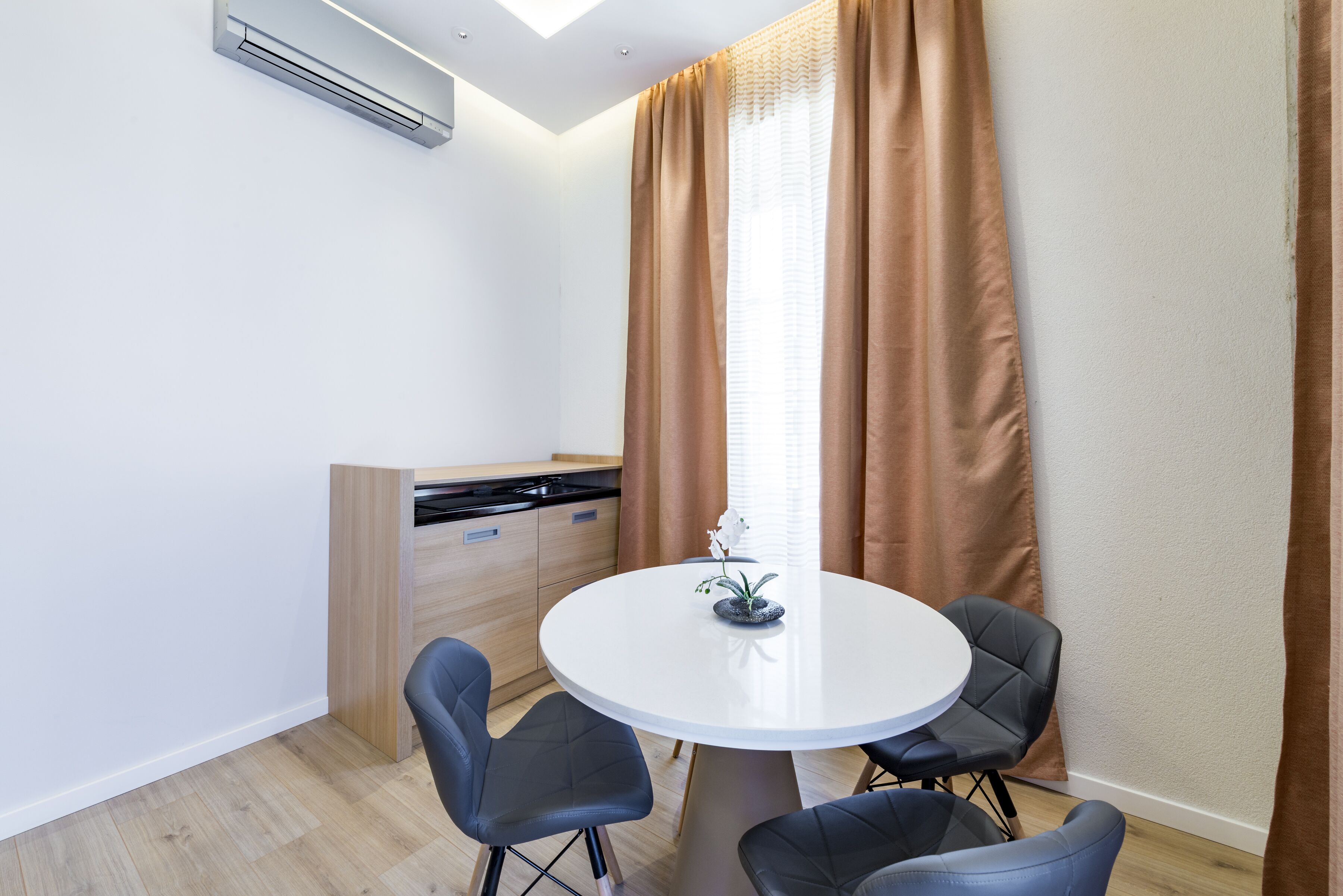 Una cocina moderna con estufa integrada, una mesa redonda con cuatro sillas y una pequeña planta en maceta sobre la mesa.