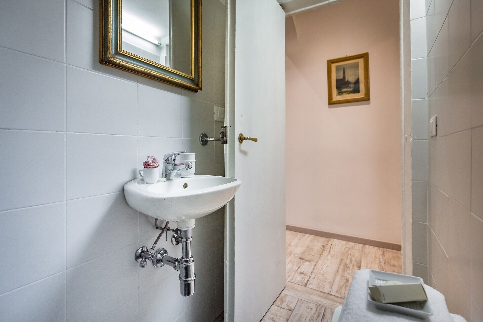 A bathroom with a white sink, a mirror, and a door leading to another room.