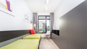 A modern hotel room with two single beds, a small table, a chair, and a view of the outdoors through a large window. - 2- bedroom Apartment near Main Market Square (kraków)