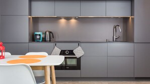 A modern kitchen with grey cabinetry, a Bosch oven, a kettle, and a sink. - 2- bedroom Apartment near Main Market Square (kraków)