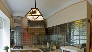 A compact kitchen with a built-in washing machine, a microwave, and a stove. - Apart Kiev Starokievskiy pereulok 5-2 (Kyiv)