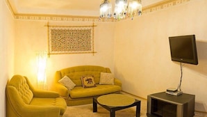 A living room with a sofa, armchair, and a coffee table. A flat-screen TV is on a stand. - Apart Kiev Starokievskiy pereulok 5-2 (Kyiv)