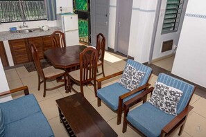 Une cuisine de taille réduite avec des meubles en bois, une table à manger et des chaises rembourrées de couleur bleue.