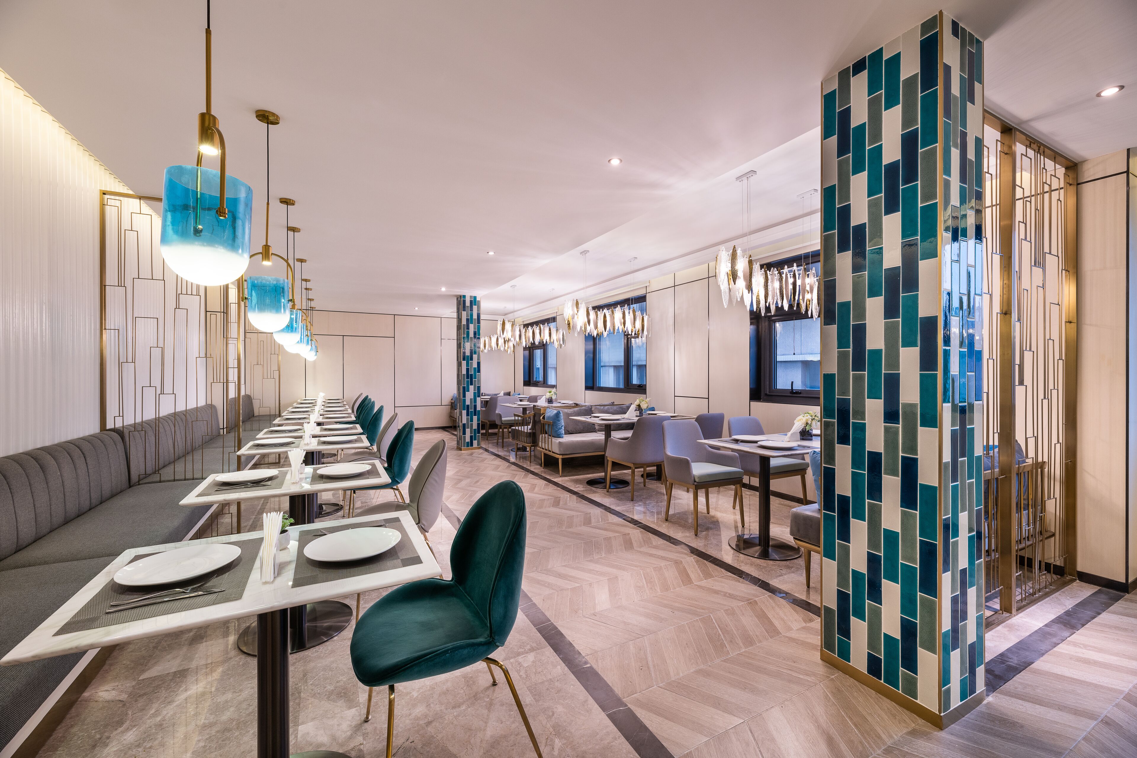 A modern dining area with long tables, teal chairs, and pendant lighting.