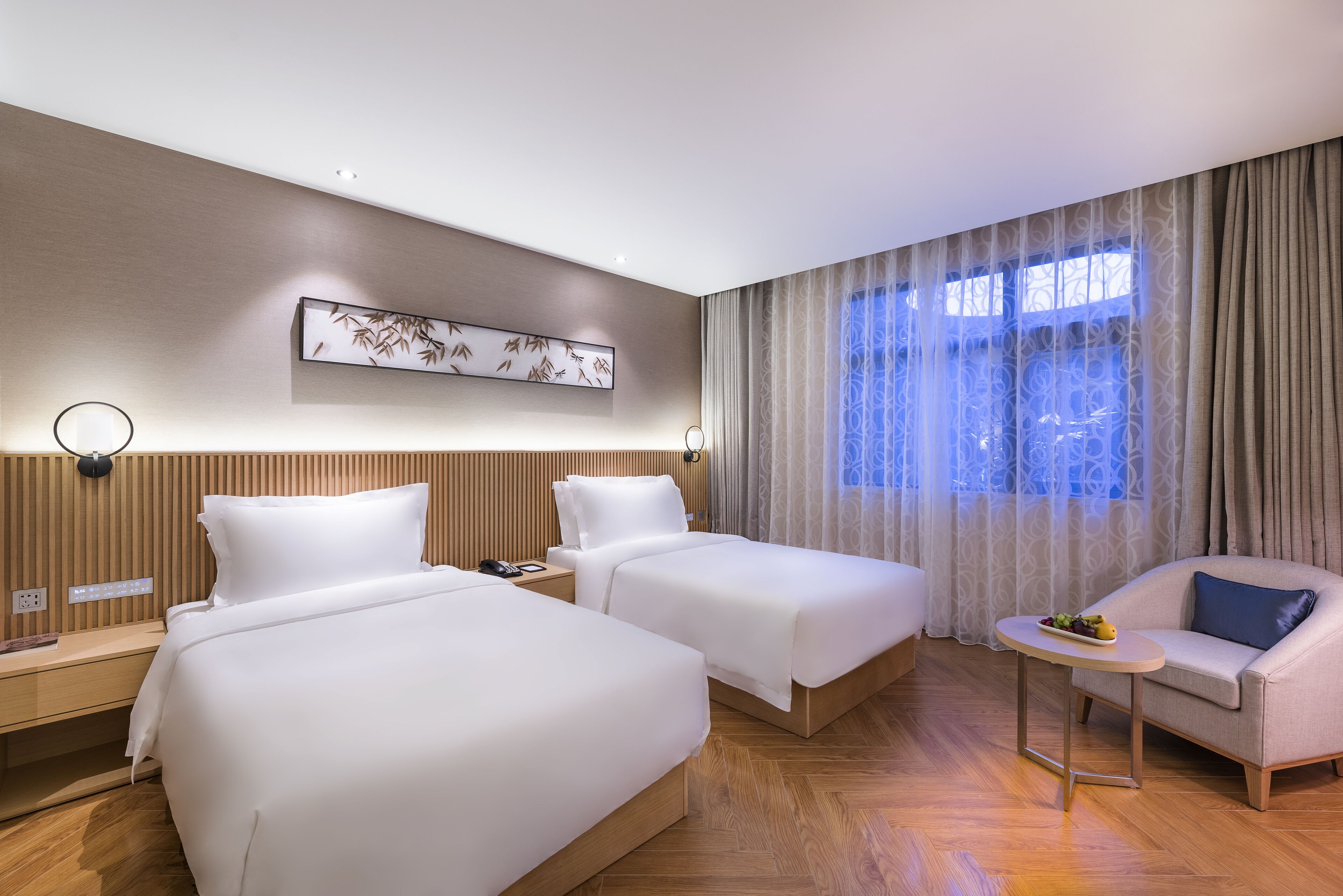 A hotel room with two beds, a sofa, a small table, and a decorative wall piece.