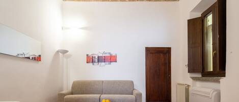 Uma sala de estar com sofá, mesa de centro com frutas, radiador e porta.