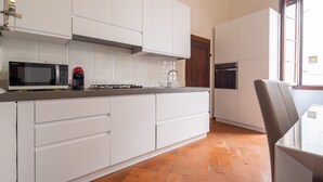 Een moderne keuken met witte kasten, een magnetron, een koffiezetapparaat en een fornuis.