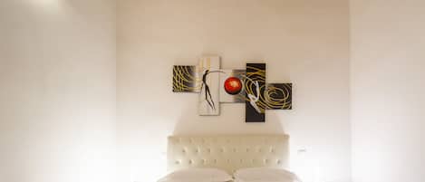 Una habitación de hotel con una cama grande, cabecera y obras de arte en la pared.