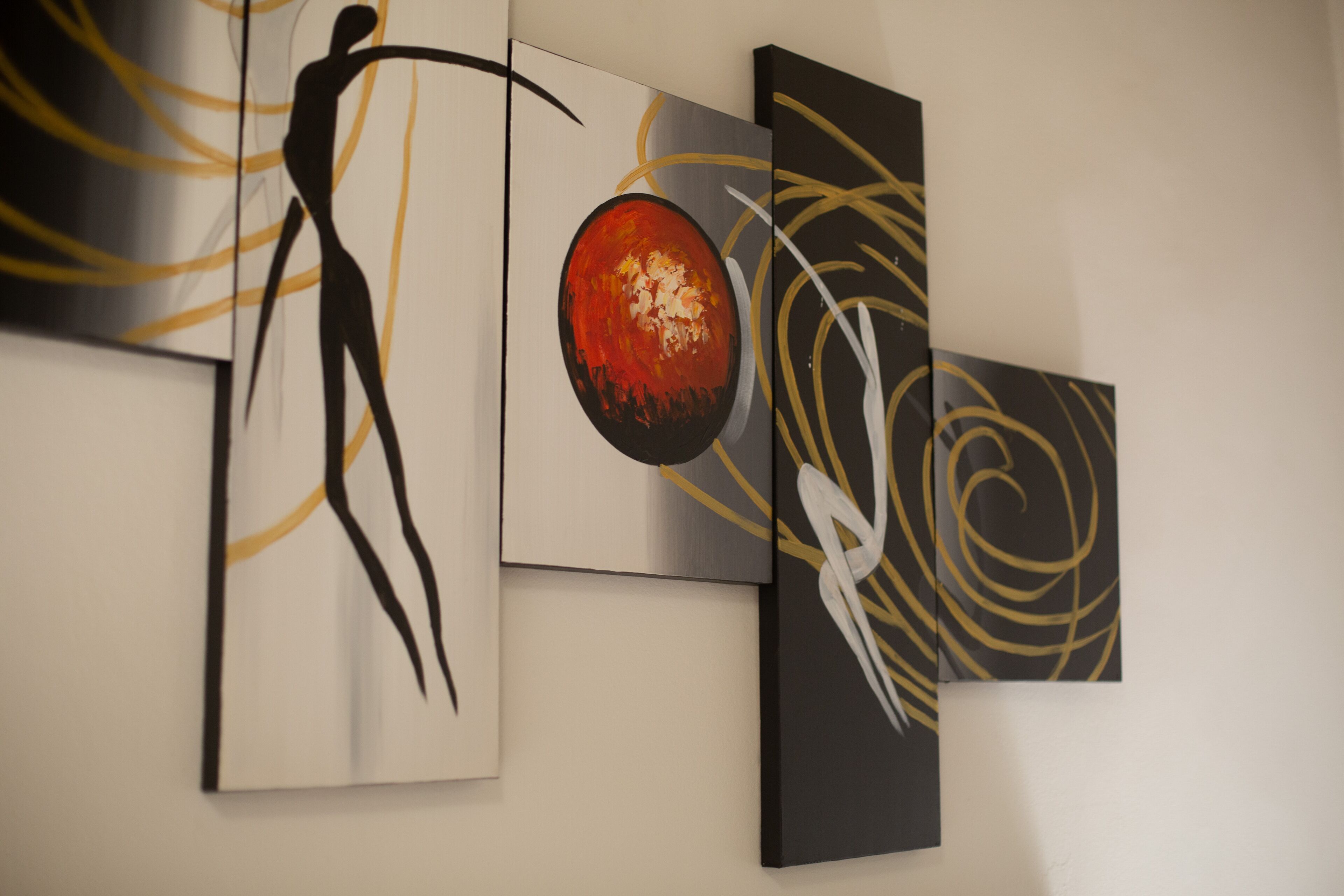 Three abstract paintings on a wall.