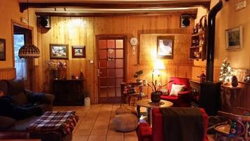 Un salón acogedor con muebles de madera, una chimenea, un sofá, un sillón rojo y una mesa de comedor.