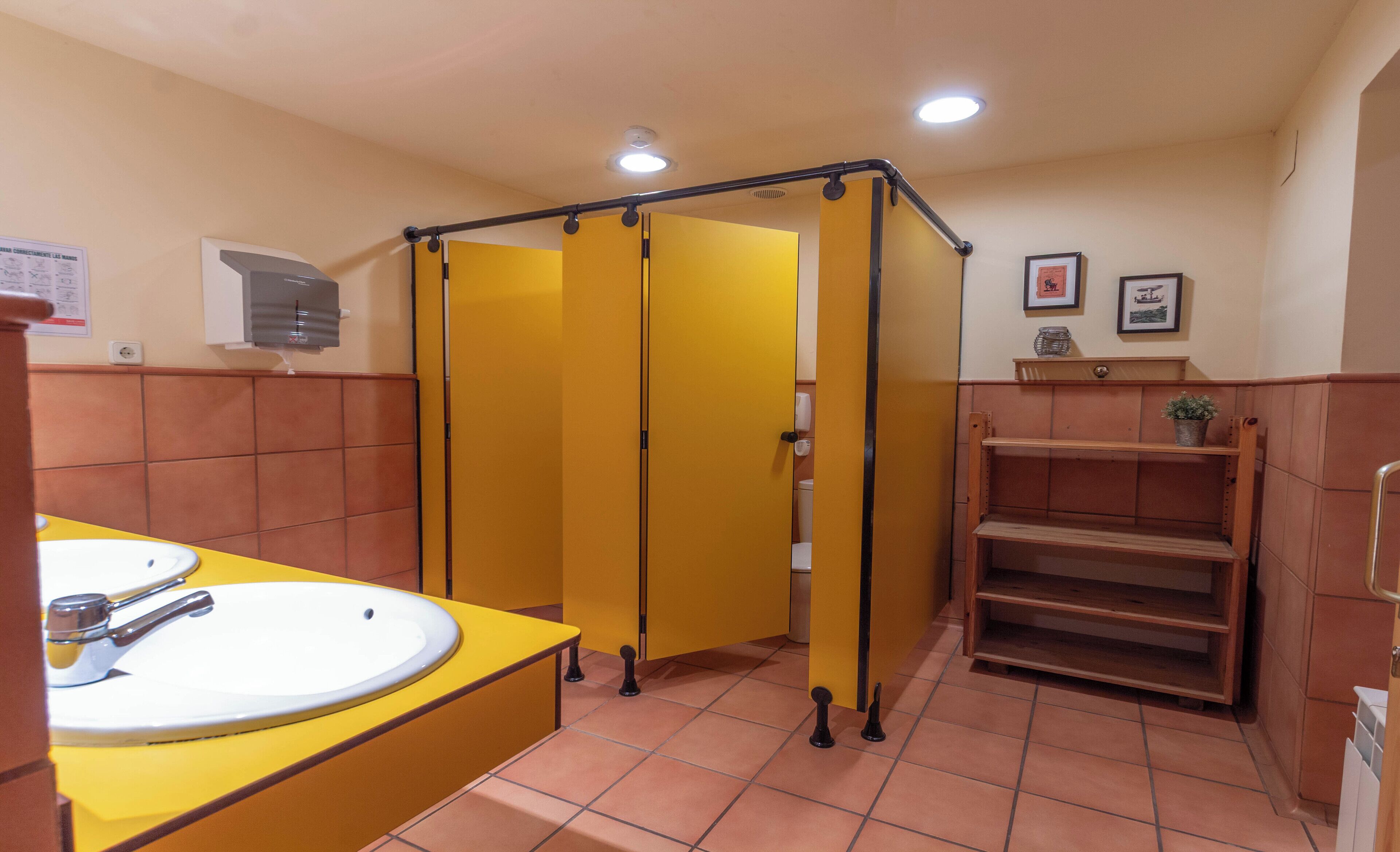 Un baño con cabinas amarillas, un lavabo y un espejo.