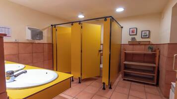 Un baño con cabinas amarillas, un lavabo y un espejo.