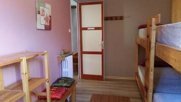 Habitación tipo dormitorio con literas, un escritorio de madera, un radiador y una puerta.