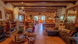 A cozy living room with a fireplace, a dining area, and a kitchen visible through an open door.