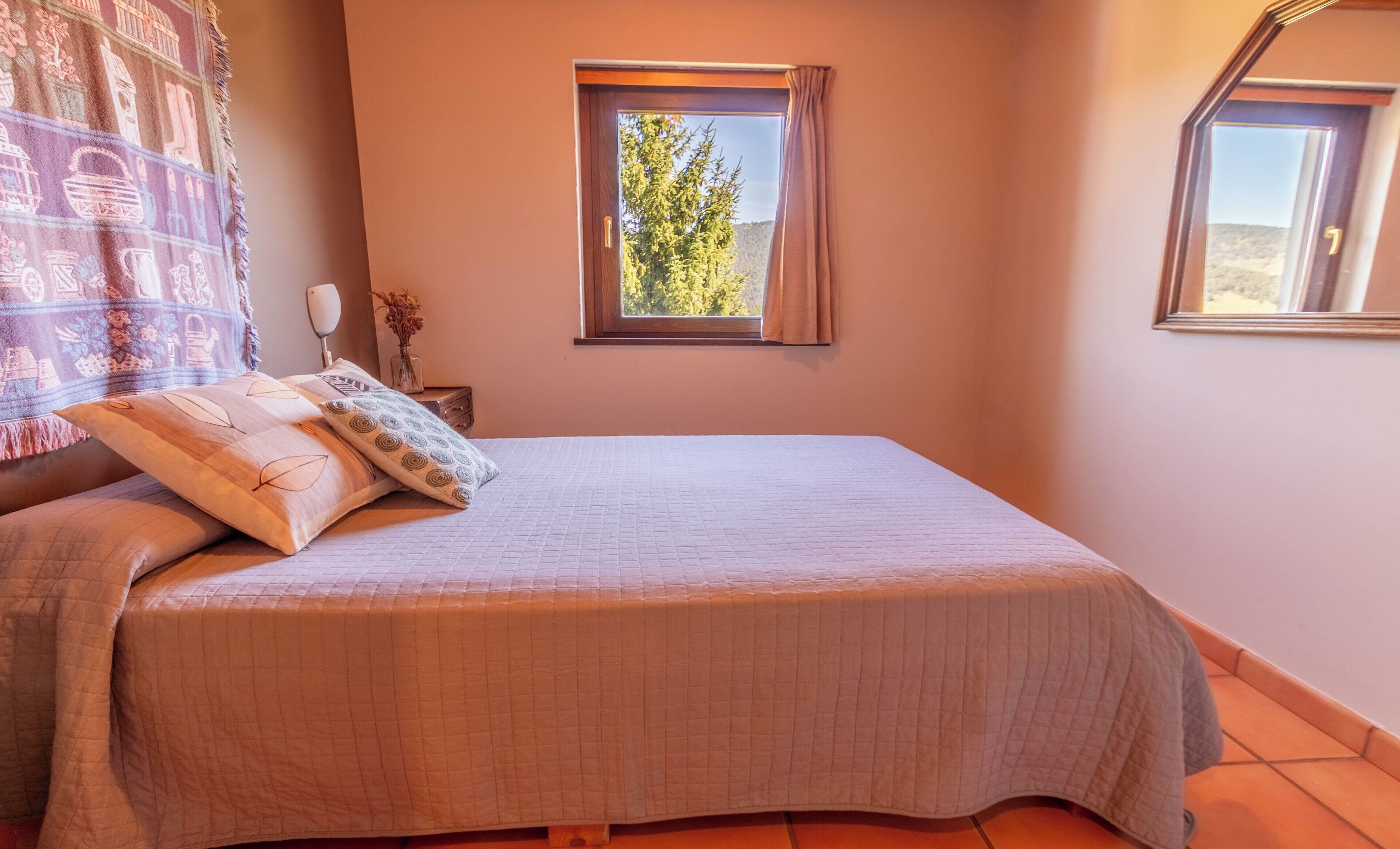 Un dormitorio con cama, ventana, mesita de noche y espejo.